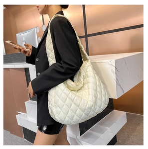 Model showing oversized cream quilted tote bag with soft diamond stitching pattern