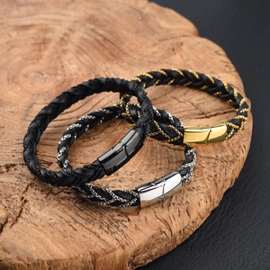 Braided leather bracelets in gold, silver and black metal finishes on a wood slice