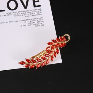 Elegant gold leaf hair clip with red marquise rhinestones on a stylish magazine background