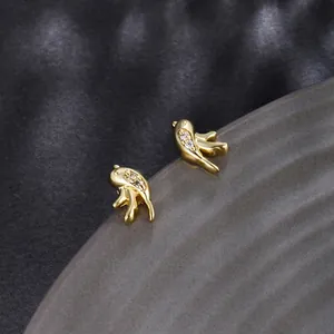 Macro detail of bird-shaped gold plated stud earrings with pavé zircon stones