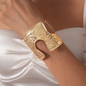 Detail view of gold hammered wide cuff bracelet with modern geometric hollow cut-outs