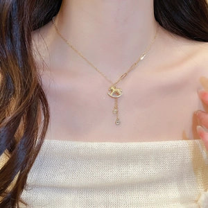 Close-up of gold-plated horse necklace with crystals and tassel on a model