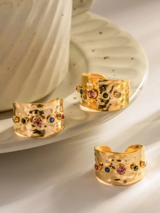 Detail eines 18K vergoldeten Hammerschlag-Rings mit bunten Zirkonia auf Creme-Porzellan