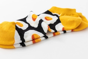 Close-up of cotton low-cut ankle socks with fried egg pattern in yellow and black