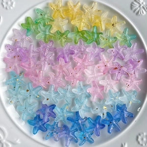 Macro shot of colorful gradient acrylic starfish beads with gold glitter for DIY crafts