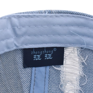 Detail view of the interior woven brand label on light blue washed denim baseball cap