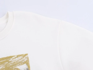 Detailed close-up of crew neckline and abstract metallic print on white cotton sweatshirt