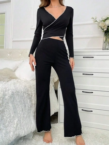 Detail of black V-neck loungewear set featuring white lettuce trim on cuffs and hemline