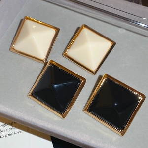 Détail de boucles d'oreilles carrées en résine noire et ivoire avec bordure dorée