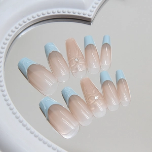 Faux ongles amande bleu et rose avec nœuds 3D et strass sur un plateau miroir