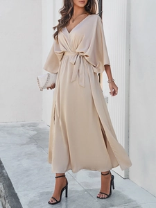 Detail view of beige v-neck dress with batwing sleeves and side slit on an elegant model