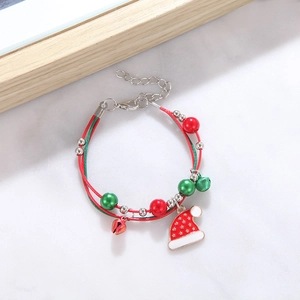 Detail of red and green woven Christmas bracelet with Santa hat and bell charms