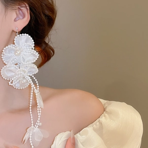 Close-up of white chiffon petal earrings with long pearl tassels on a model