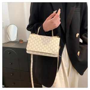 Chic beige crossbody bag with M-pattern print shown styled on a model's shoulder