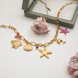 Detail of gold starfish and seashell charms on a layered ocean-themed necklace