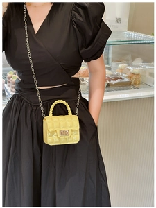 Close-up of bright yellow quilted PVC jelly bag featuring a gold twist lock and chain strap