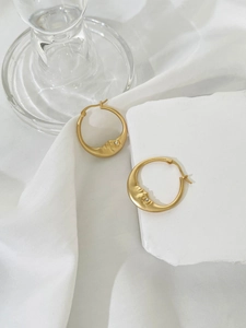 Detailed view of crescent moon face earrings in gold finish with small rhinestone accents