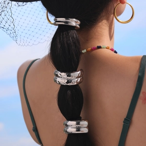 Dreiteiliges silbernes Metall-Haargummi-Set an einem Model vor blauem Himmel gezeigt