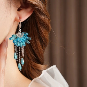Gros plan sur les boucles d'oreilles bohèmes fleur en cristal bleu avec pompon argenté