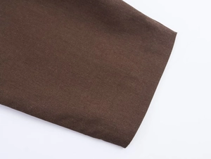 Close-up of the brown woven fabric texture and stitching details on a casual jacket cuff