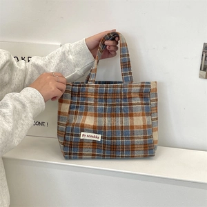 Detail of retro plaid tote bag with blue and orange tweed texture and logo label