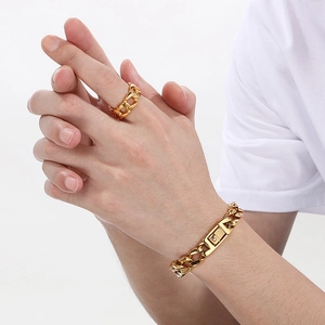Detail of men's gold-plated Cuban link bracelet and matching ring on model's hand