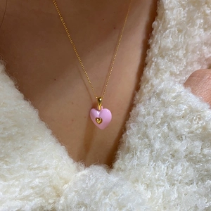 Close-up of pink heart enamel pendant necklace with gold chain on model neck