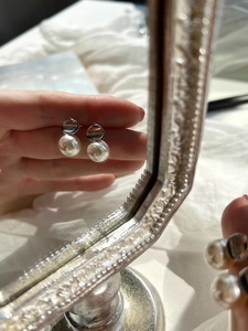Macro detail of elegant S925 silver pearl earring held by hand for scale reference