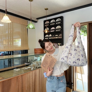Lifestyle shot of white lace butterfly tote bag held by a model in a cozy cafe setting
