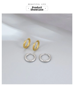Detail of gold and silver hammered hoop earrings on soft blue silk fabric