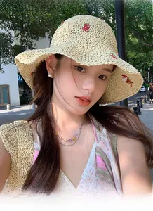 Detailed view of beige straw hat featuring embroidered strawberry patterns for sun protection