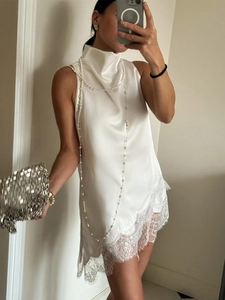 Detail of white satin sleeveless top featuring cowl neck and delicate lace trim hem