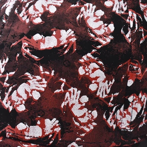 Detailed close-up of woven canvas fabric with red and black crab pattern on a baseball cap