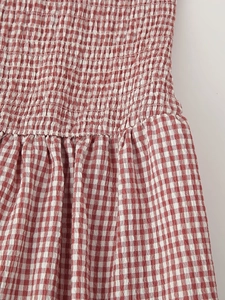 Detailed close-up of the red and white gingham fabric with elastic smocking stitch