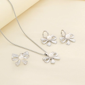 Detailed set of silver bow jewelry with pearls including necklace, ring and earrings