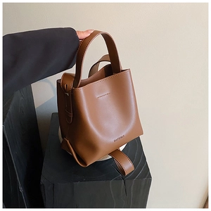 Close-up of brown leather bucket bag showing decorative stitching and matte finish details
