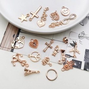 Variety of KC gold charms like stars and planes for DIY necklaces on ceramic plate