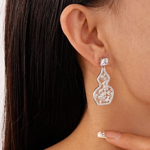 Detail of silver gourd earrings with zircon and rose carving worn by a model