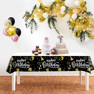 Detail of black and gold Happy Birthday tablecloth with festive balloon and cake patterns