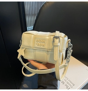Détail du sac tressé en similicuir blanc cassé avec breloque étoile et chaîne métal