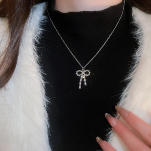 Detail of silver bow pendant necklace with crystals worn on a model's neck