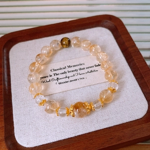Detailed shot of yellow citrine and tiger eye beaded bracelet on a vintage wood tray