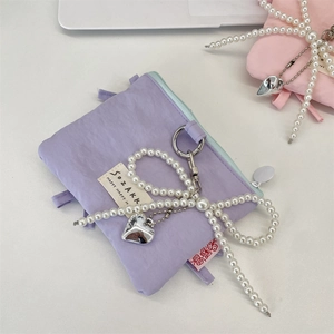 Dettaglio porta carte in nylon viola con fiocco di perle e ciondolo a cuore
