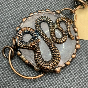 Detailed macro view of retro bronze snake pendant with translucent white gemstone crystal