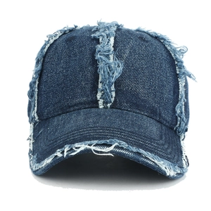 Macro detail of distressed edges and frayed stitching on deep blue denim baseball cap