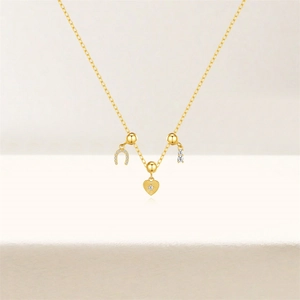 Detailed view of gold necklace with horseshoe, heart, and geometric zircon pendants