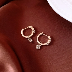 Vue détaillée de boucles d'oreilles fleur en zircon doré sur satin sombre élégant