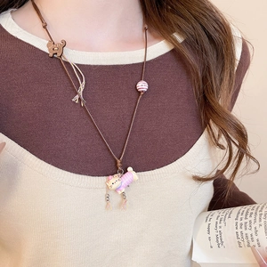 Close-up of cute cartoon cat pendant with colorful fringe and beaded brown leather cord
