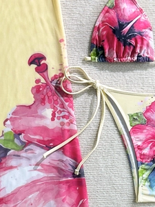 Detailed close-up of vibrant tropical hibiscus print bikini set with long sarong wrap