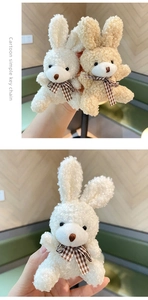 Close-up of white and beige plush bunny keychains with checkered bow ties in hand